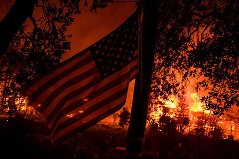 Us flag flies in front of wildfire
