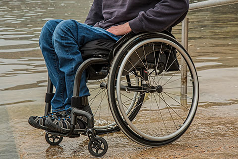 Person in wheelchair near flooded road